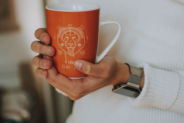 woman holding ceramic mug with leo zodiac sign