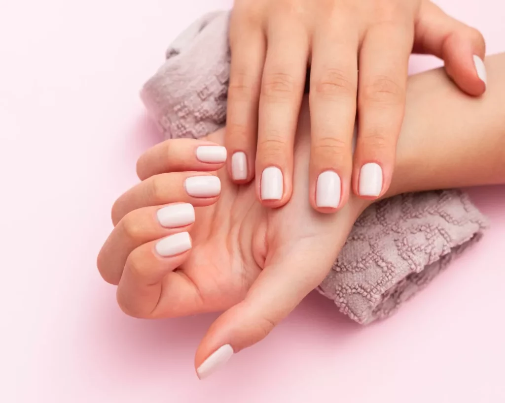 Close up photo of hands with White nail polish